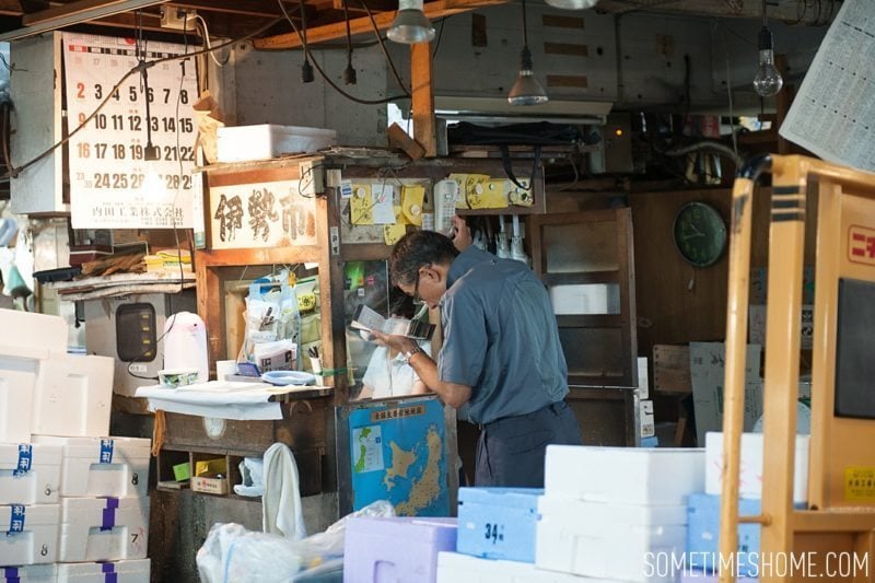 Experience and photos at Tsukiji Fish Market in Tokyo, Japan by Sometimes Home Travel Blog. Picture of vendors stands in the market.