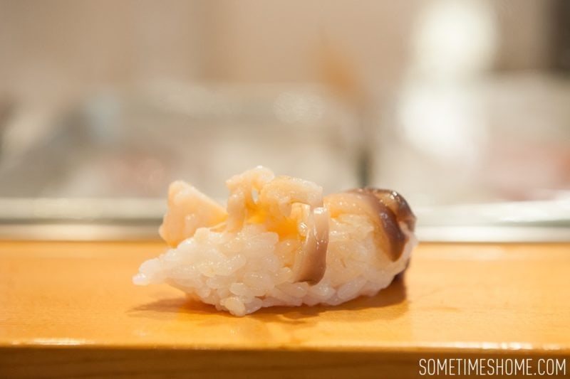 Sushi Dai Restaurant at Tsukiji Fish Market in Tokyo Japan. Photos on Sometimes Home travel blog with a picture of a piece of surf clam sushi.