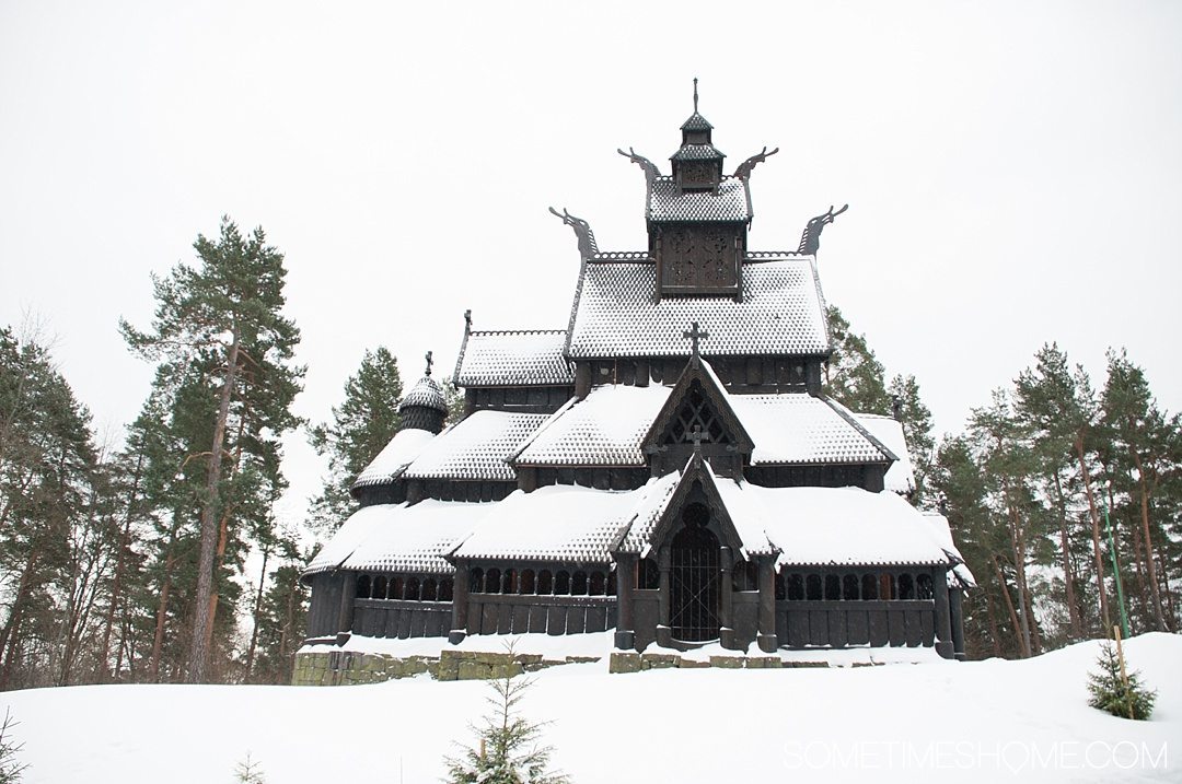 Reasons Why January is the Best Time to Visit Norway with a photo of a traditional wooden Stave Church covered in snow in Oslo's Norsk Folkemuseum.