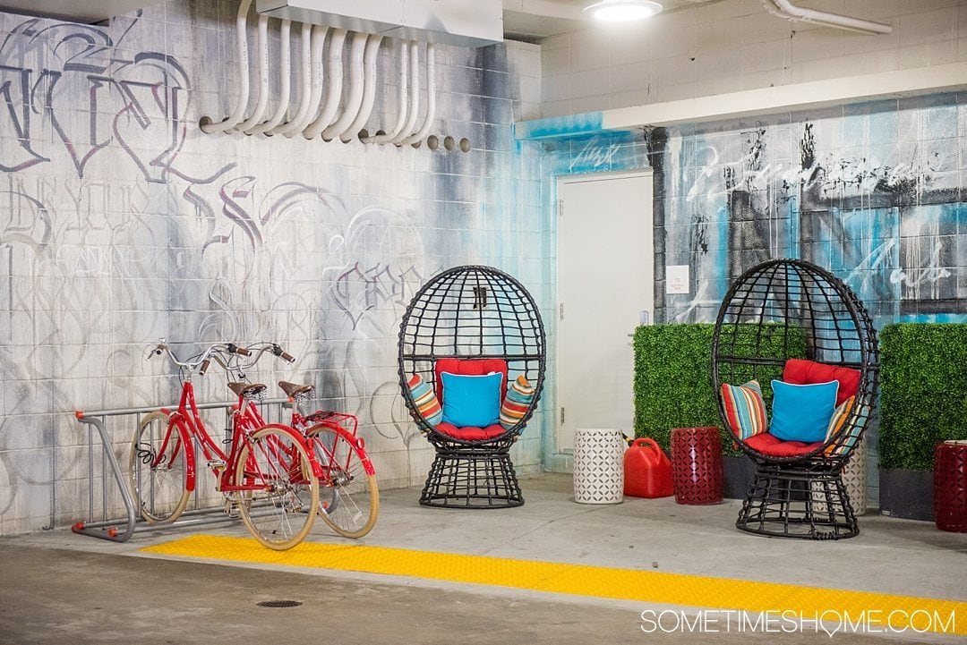 Unscripted Hotel Review Durham in North Carolina. Photos and information on Sometimes Home travel blog. Picture of the interior garage entrance. Bright colors, chairs and graffiti set the stage.