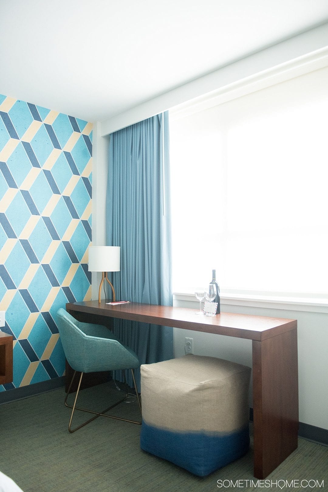 Unscripted Hotel Review Durham in North Carolina. Photos and information on Sometimes Home travel blog. Picture of the hotel room features including a desk area with colorful mid-century modern features and pattern accent wall.