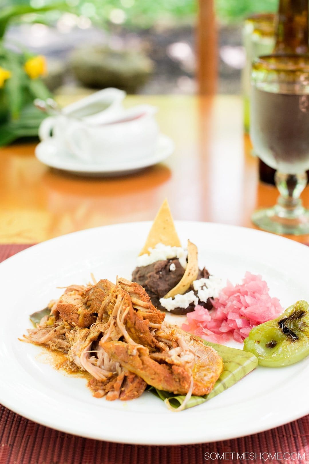 6 Unique Foods to Try in the Yucatan Peninsula on Sometimes Home travel blog. Photos of Cochinita Pibil, served with pickled onions and black beans.