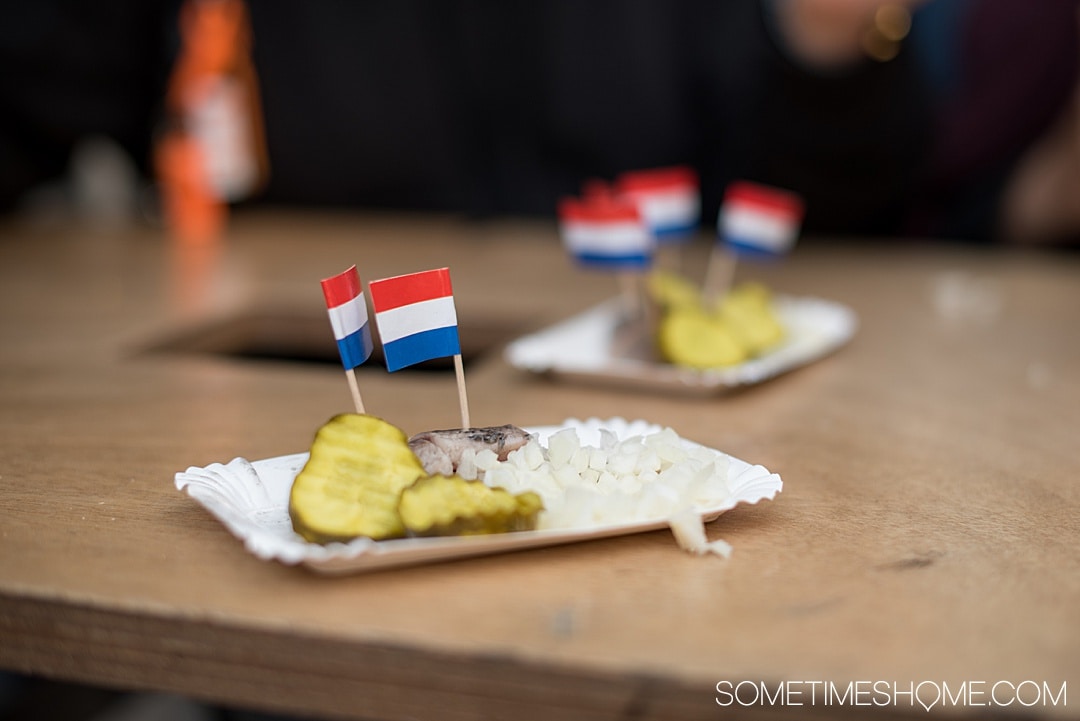 Traditional Dutch foods and drinks to taste in The Netherlands. From Amsterdam desserts to drinks in Holland, cheese in the countryside and more we have your list of snacks and sweets to taste including Herring fish, mini pancakes poffertjes, and stroopwafels. #SometimesHome #TheNetherlands #TraditionalFoods #Dutch #Holland #TypicalCuisine #DutchBeer #DutchFood #AmsterdamArea