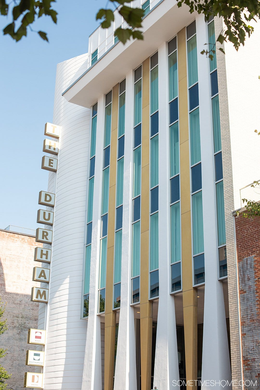 Downtown Durham, NC hotel decorated in Mid-Century Modern style. Check out photography of The Durham Hotel, the complete package. With a restaurant with James Beard Award Winning Chef, Rooftop Yoga with views of the skyline and great nightlife and cocktails. It's 30 minutes from Raleigh and a great staycation weekend getaway option too. #SometimesHome #MidCenturyModernHotel #RooftopBar #DowntownSkyline #DurhamNC #DurhamNorthCarolina