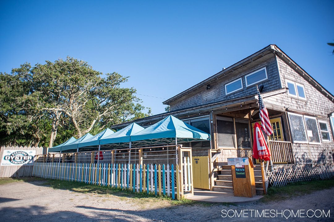 Blue sky with a restaurant building and blue sátor covers out front.