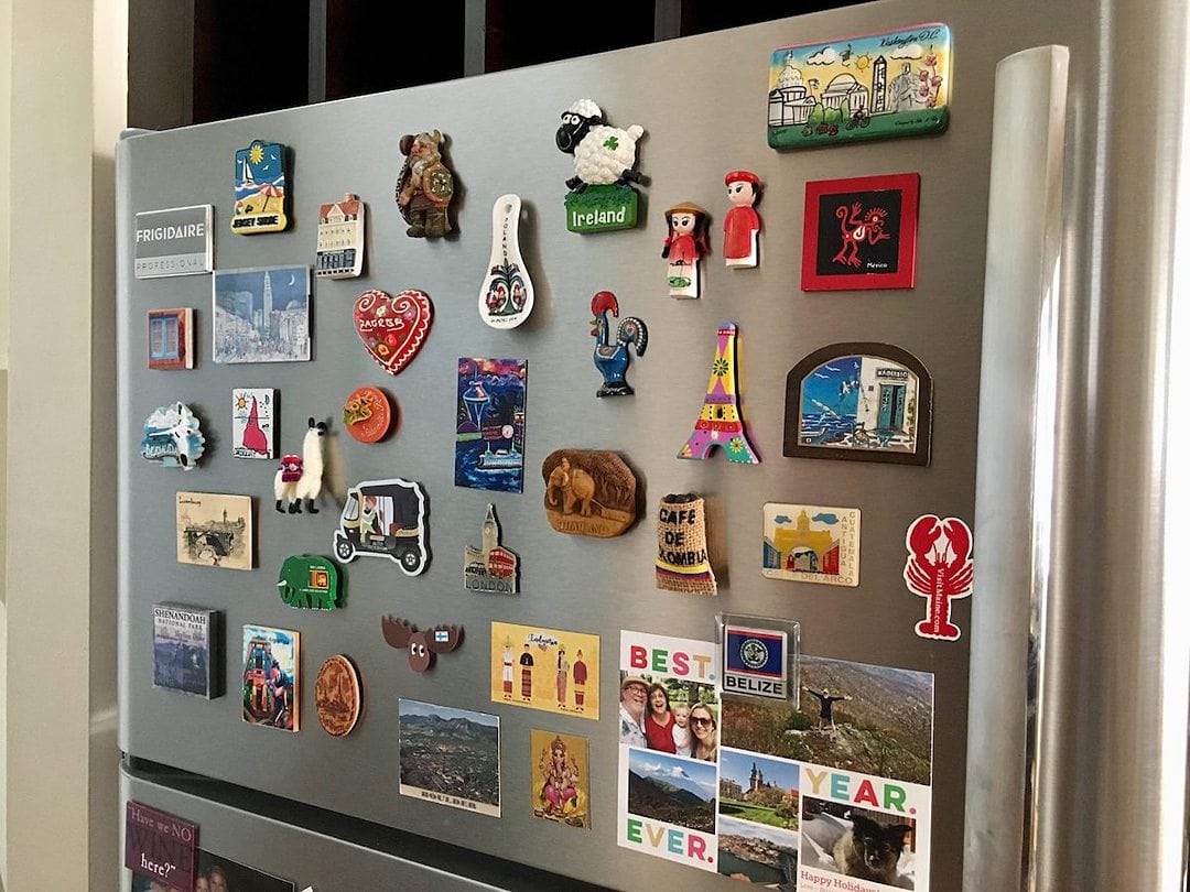 Souvenir magnets from destinations around the world on a refrigerator.