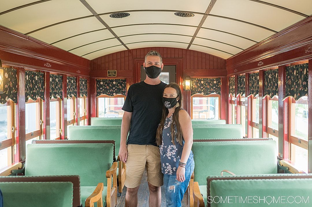 Inside of an old train car and a couple in the middle of the seats