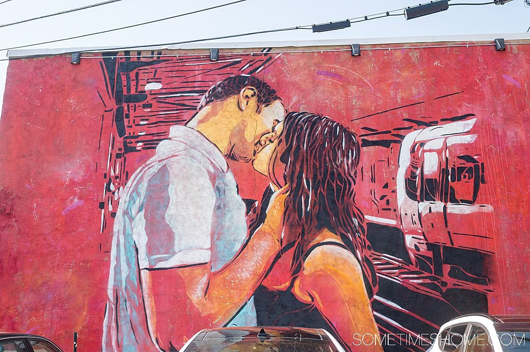 A mural with a red background with a couple kissing