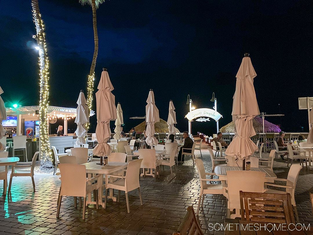 Dark sky and collapsed oversized patio umbrellas with table and chairs at an outdoor restaurant.