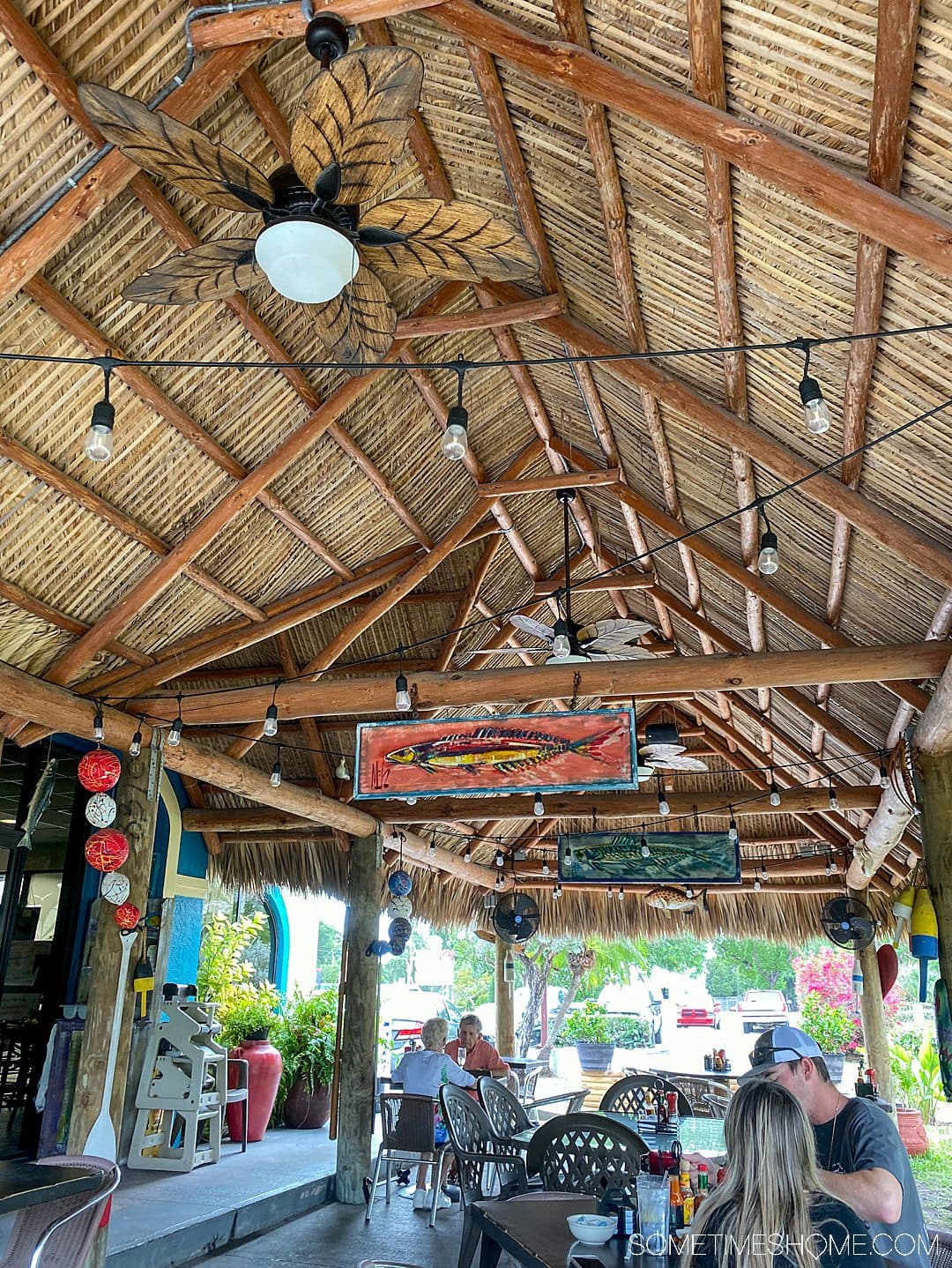 A roof above diners at a restaurant in Key Largo, FL and two fish paintings in the rafters.