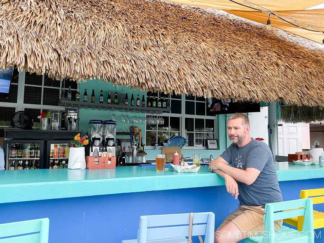 A man at a blue and turquoise painted bar in Florida.