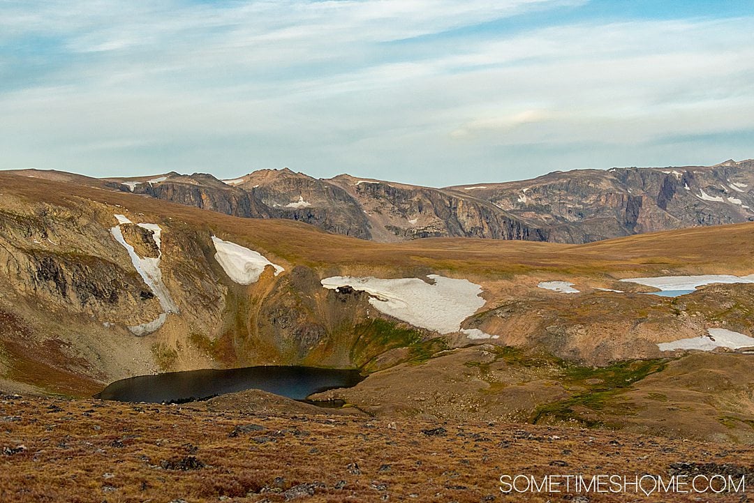 Icy areas amongst brown and yellow colored mountains with a blue sky.