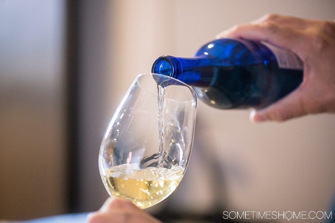 Pouring a blue bottle of white wine made with North Carolina muscadine grapes into a wine glass