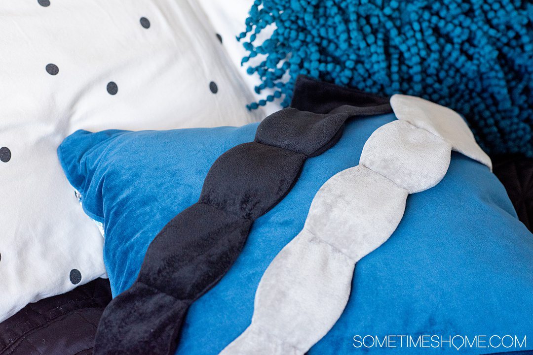 nodpod sleep masks in grey and black on a blue pillow.