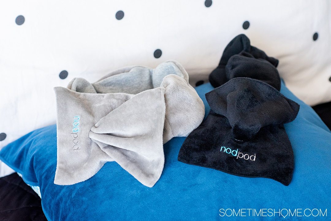 nodpod sleep masks in grey and black on a blue pillow.