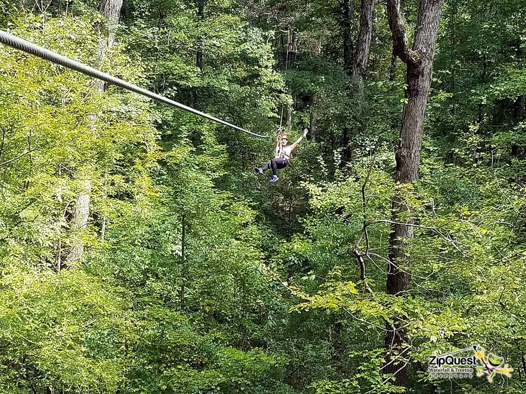 A woman ziplining in the trees at ZipQuest in Fayetteville, NC.