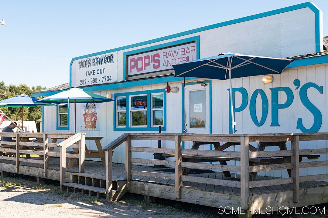 The front of a blue and white building, one of the best seafood restaurants in the Outer Banks, that says "Pop's" on the side.