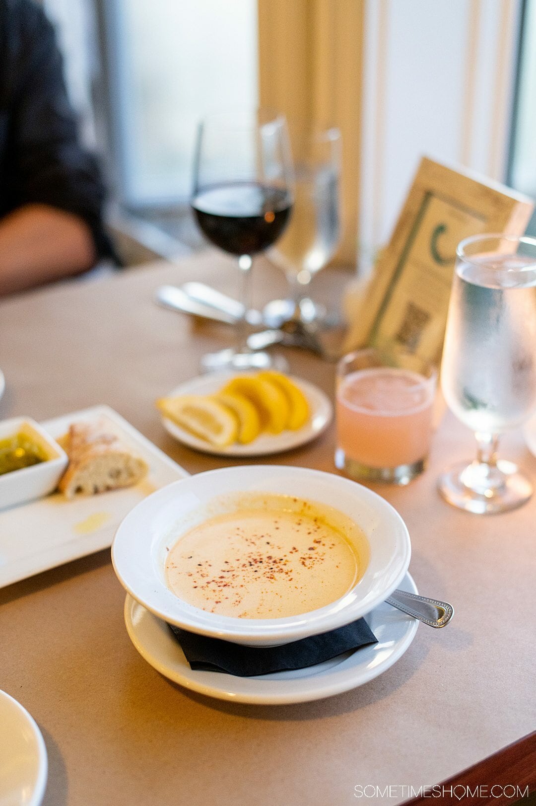 A bowl of crab soup and a glass of red wine in the background at one of the best seafood restaurants in the Outer Banks.