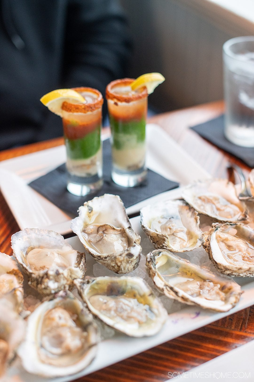 A plate of raw oysters with two oyster shooters in the background at the Blue Water Grill & Raw Bar in the Outer Banks.