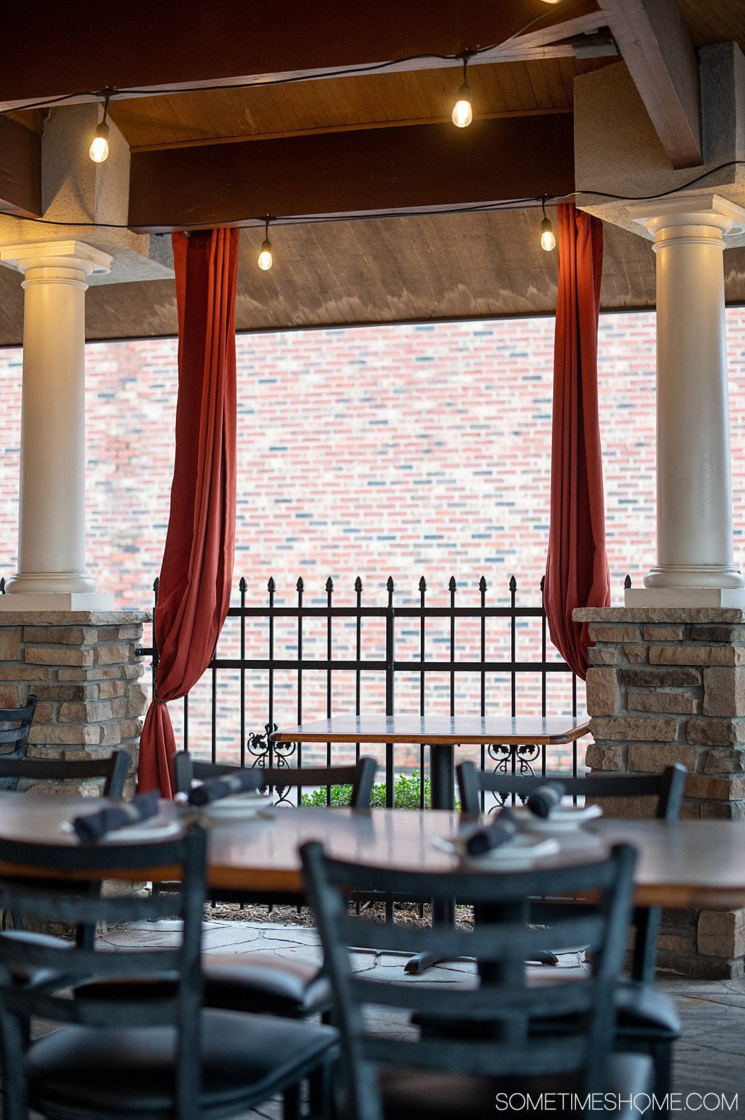 Red curtains and white columns on an outdoor patio at the restaurant Luigi's in Fayetteville, NC.