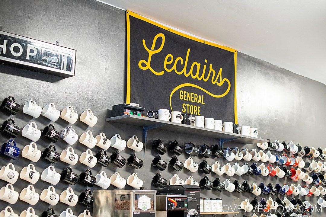 A wall of black and white mugs with a "Leclairs General Store" flag above it in Fayetteville, NC.