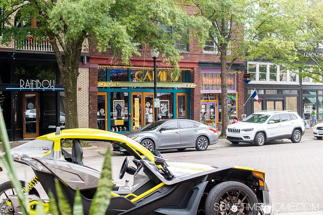 Cars on the street and a coffee shop called Rude Awakening in the distance with a colorful facade for date ideas in Fayetteville, NC. 