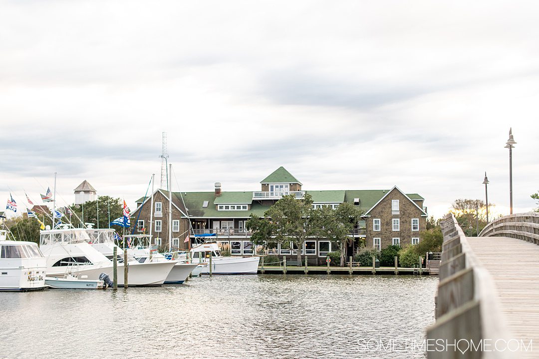 View of a hotel from a bridge on the water, with boats on the left.