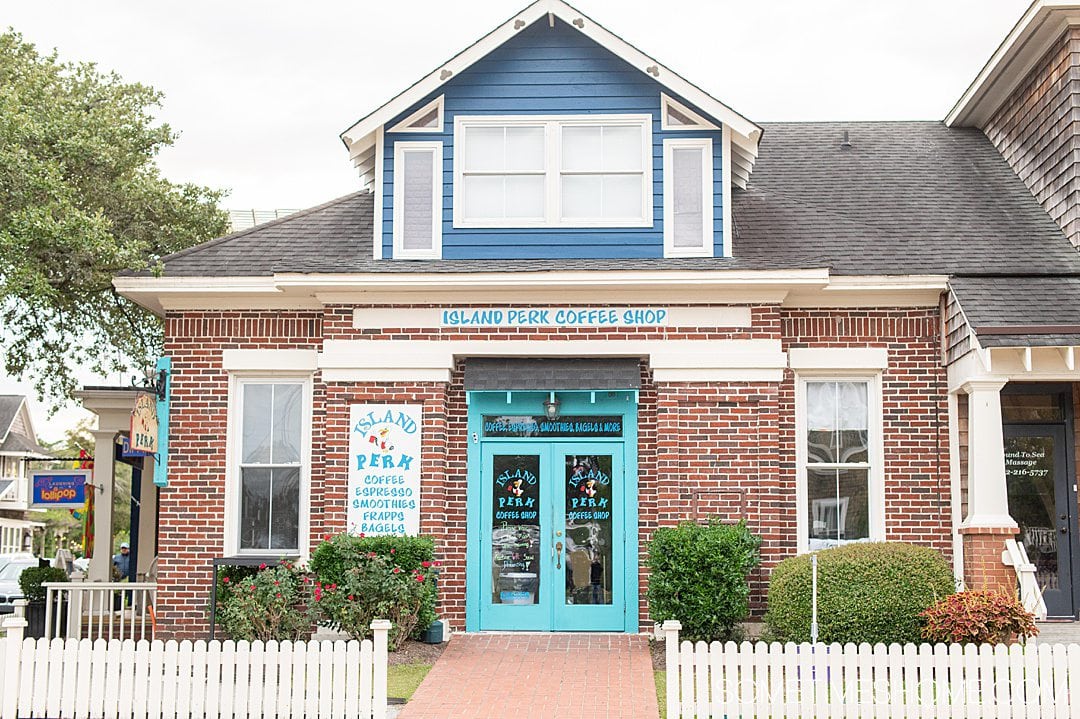 Island Perk Coffee Shop with a brick building and turquoise doors and a white picket fence in downtown Manteo in the Outer Banks.