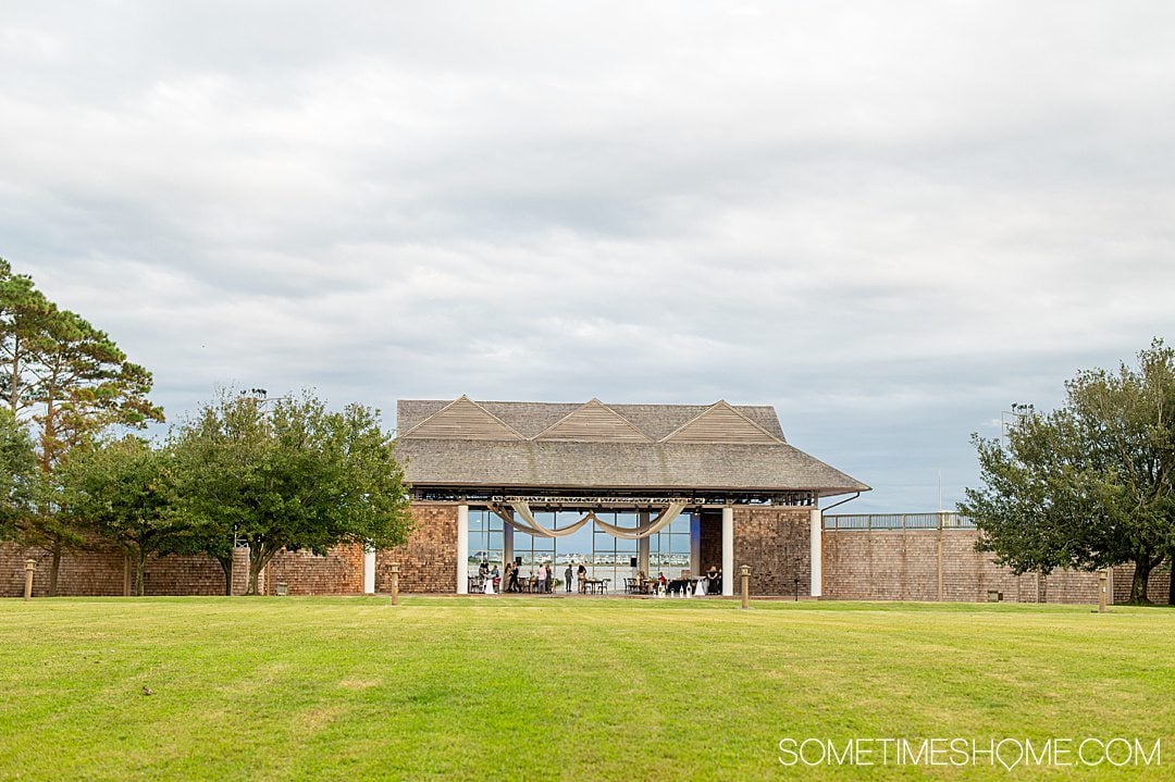 A green lawn in the foreground and blue sky, with an open walled structure in the distance at Festival Park in the Outer Banks of North Carolina.