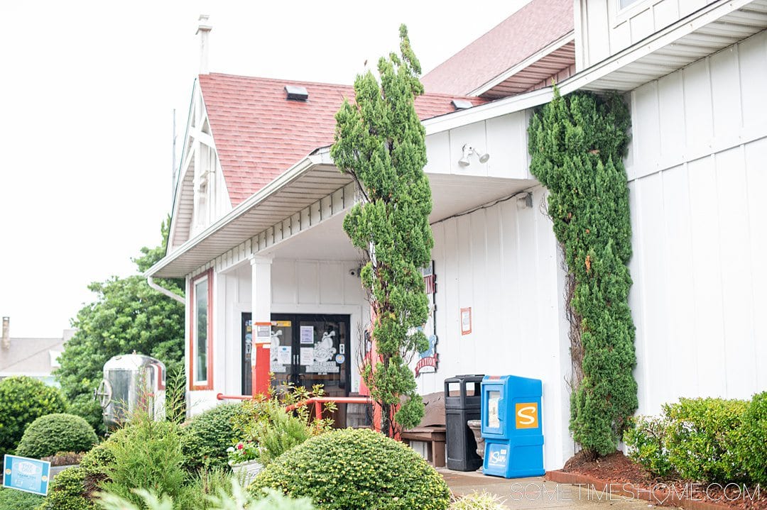 Photo of the exterior of a brewery in the Outer Banks of North Carolina with green trees out front of a white building.