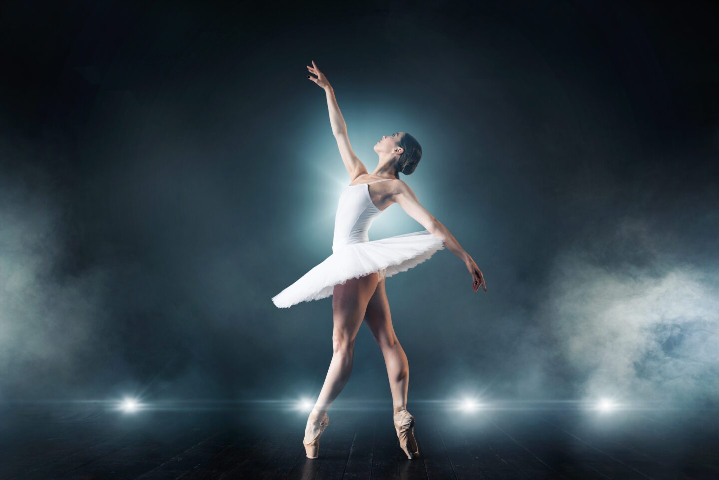 Ballet dancer in white dress dancing on the stage in theatre. Graceful ballerina training in class