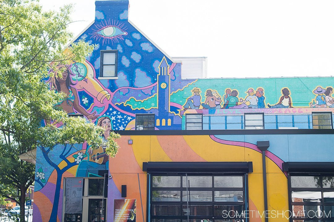 Colorful mural on the side of a three story building, with 1960s inspired shapes and themes.