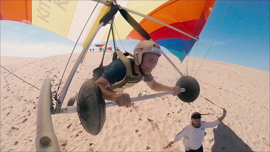 A man hang gliding with a gold helmet on in the Outer Banks in North Carolina.