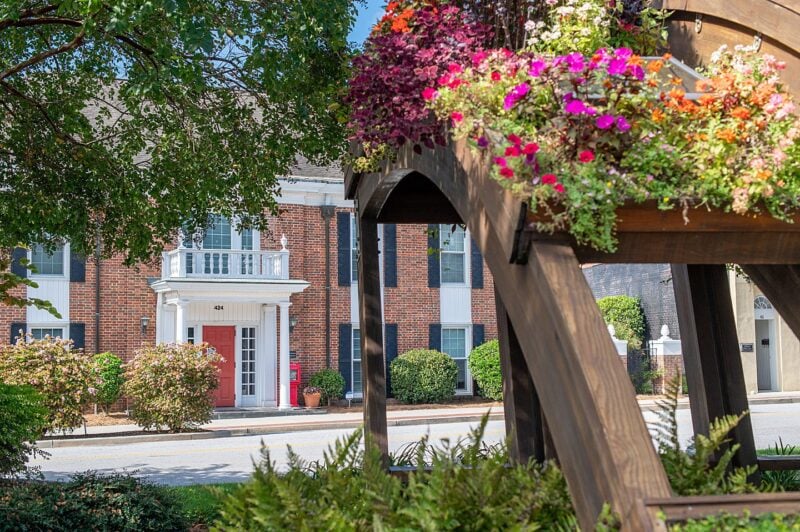 Colorful flowers on a brown wood structure and brick building with a red door in the background in the Old 96 District of South Carolina.