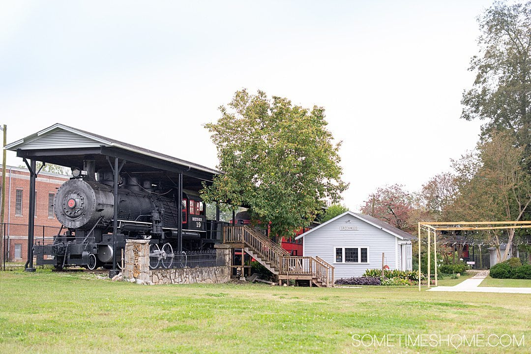 A locomotive on the left and small house structure on the right at a historical Railroad center in Greenwood, South Carolina in the historic Old Ninety Six district.