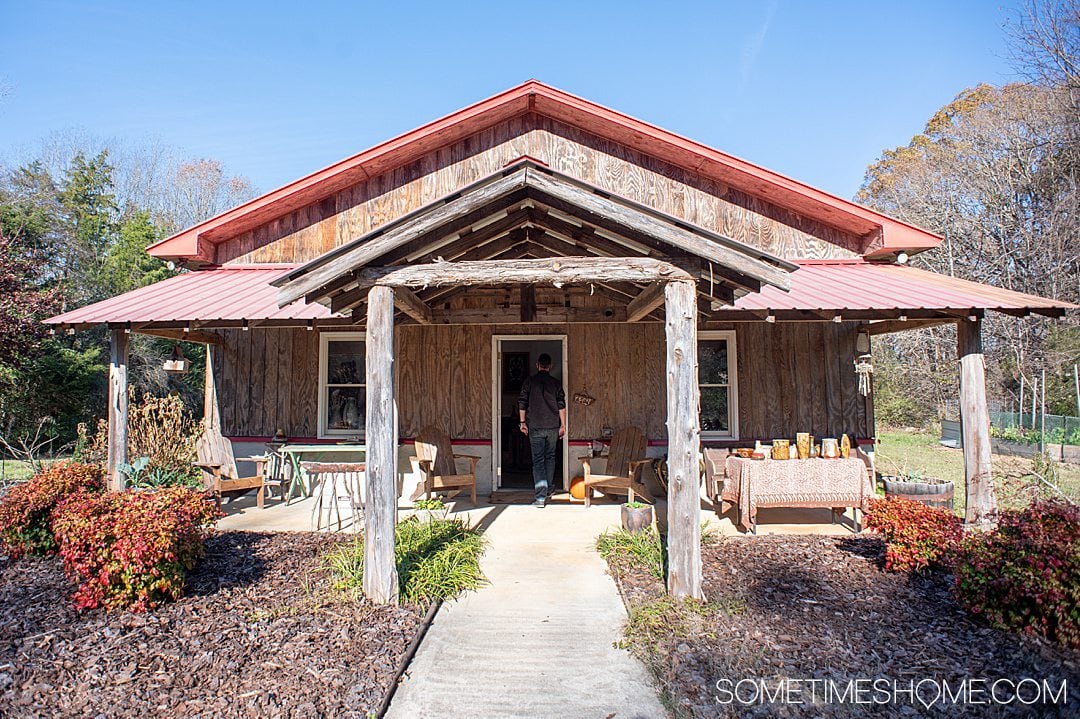 Exterior of a cabin-like building with a red roof and blue sky above it. It's the Seagrove pottery studio of Dean & Martin Pottery in NC.