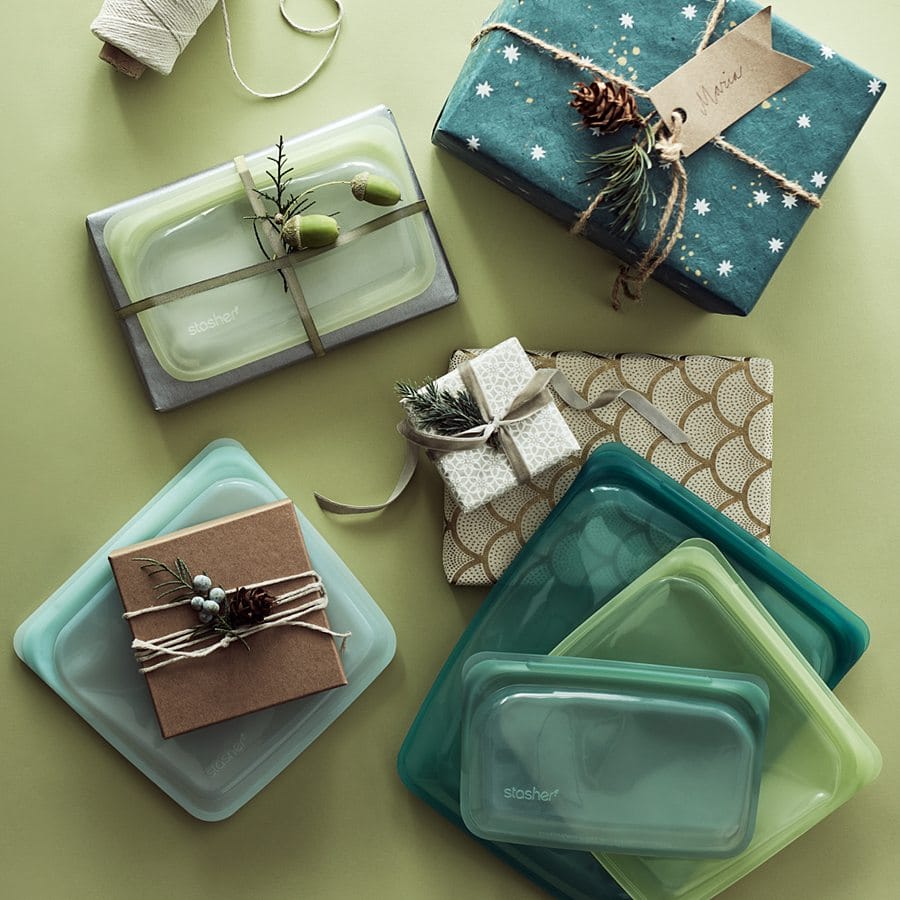 Stasher reusable silicone bags and presents in green colors, wrapped with jute and holiday paper.