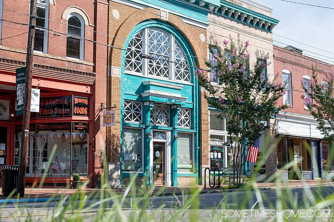 Brick building with shops in Warrenton, NC. The blue arch store is Drip Coffee + Market on Main Street downtown.