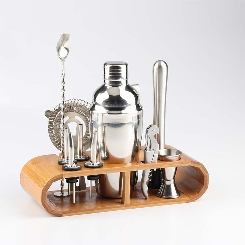 Bartending kit with silver pieces in a wooden stand.