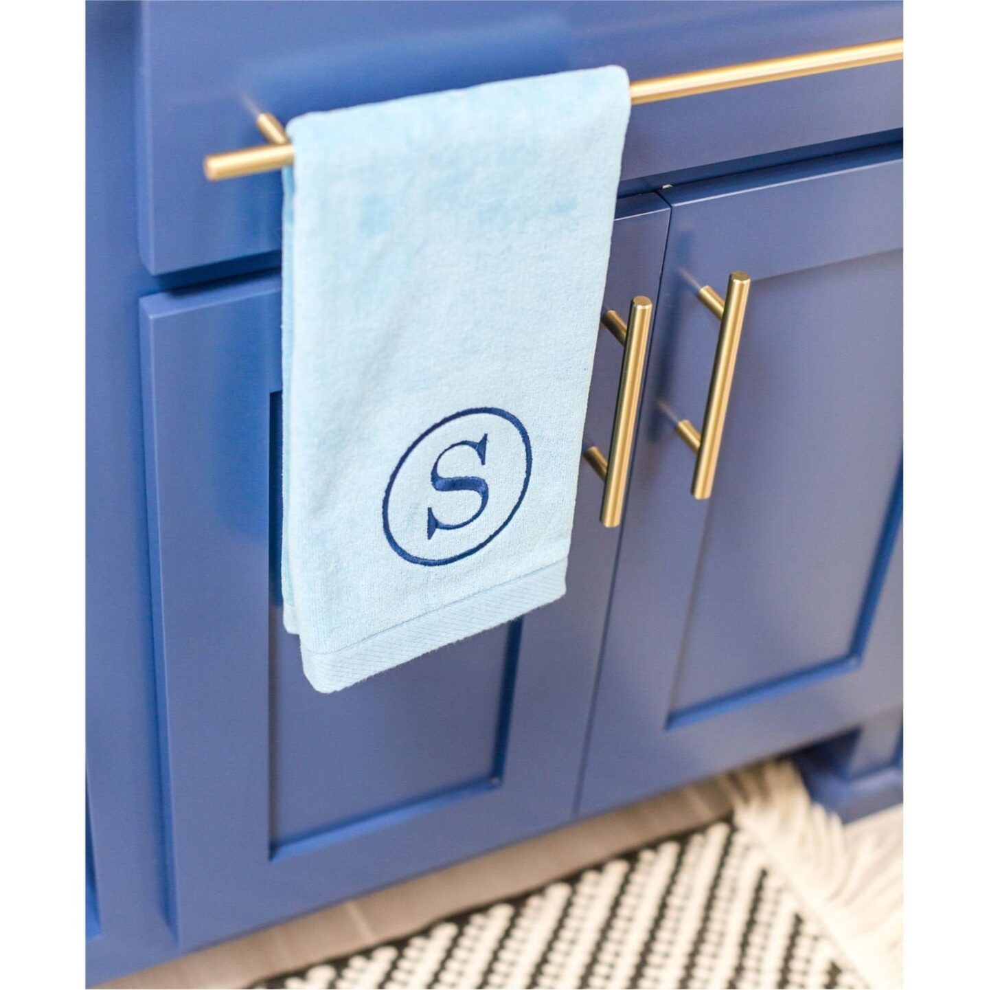 Light blue hand towel with an "S" monogram in a circle in dark blue embroidered thread.