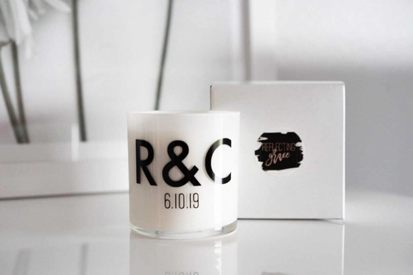 Modern block letters monogram on a candle that says R&C in black against a white glass candle.