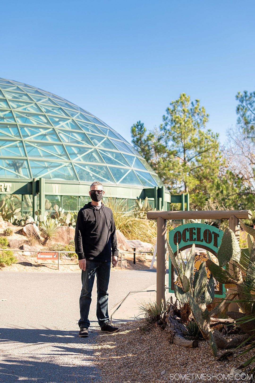 A man standing next to an "Ocelet" sign at the NC Zoo in Asheboro, NC.