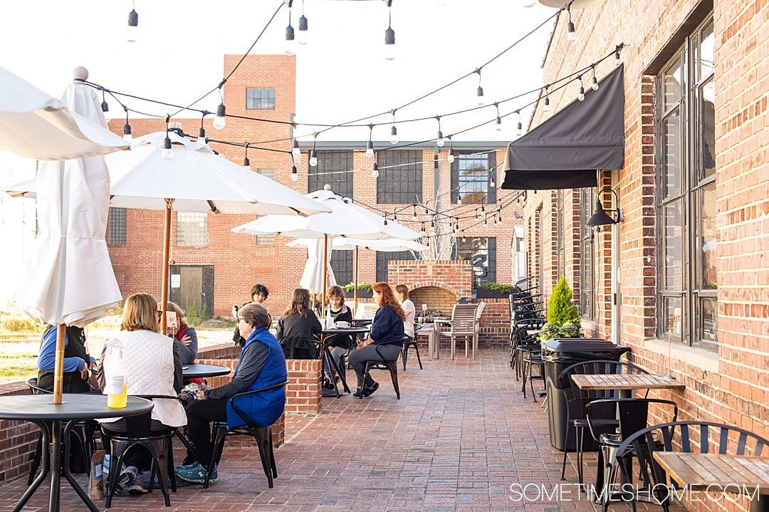 Outdoor seating area and brick walls of The Table restaurant in Asheboro, NC with string lights hung about the diners. 