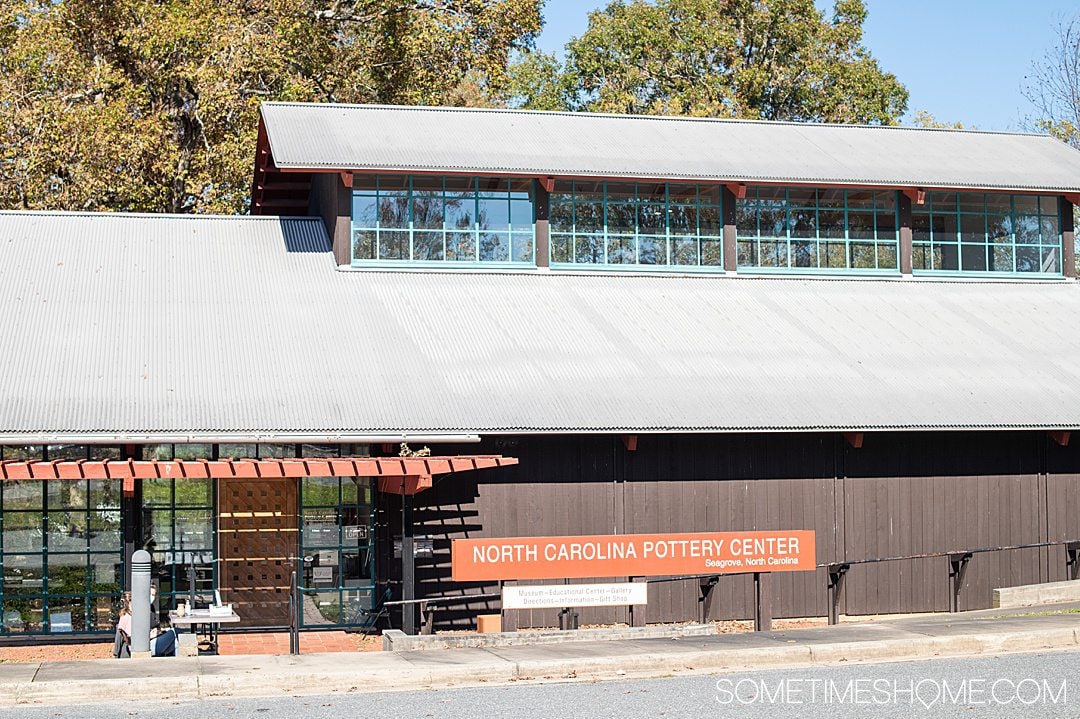 Front of the North Carolina Pottery Center building, with a red sign in front of the brown building.