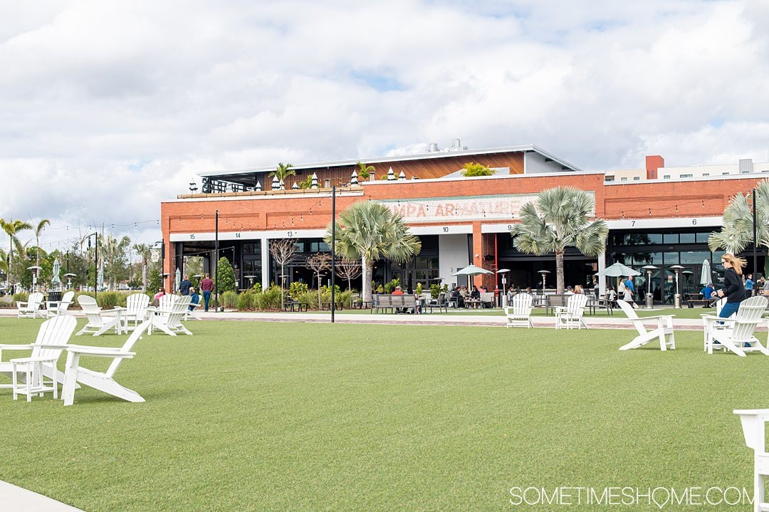 Green lawn with a brick building and palm trees in the background at Armature Works in Tampa.