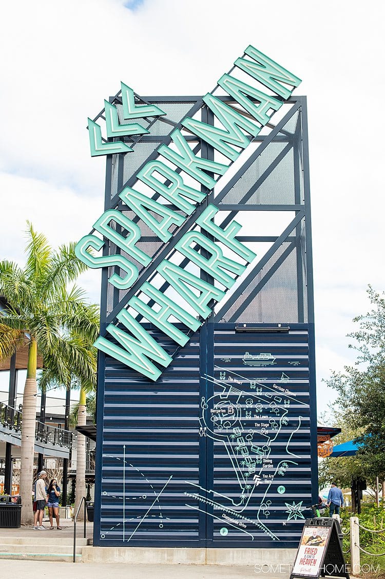 Sparkman Wharf sign on a tower, in mint green letters on a navy blue structure in Tampa, Florida.