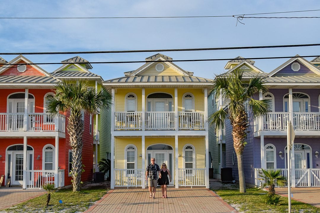 Three colorful homes with a balcony, and a couple walking in the center. 