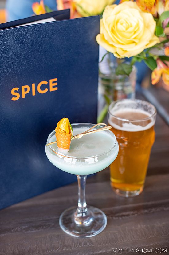 Photo of a martini glass with a blue drink and pint of beer in front of a blue menu that says "Spice," at a restaurant in Fort Mill, SC.