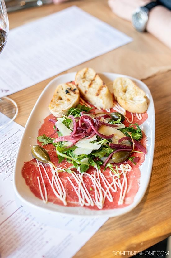 A plate of beef carpaccio and toasted bread with a salad in the middle at Napa Kingsley, at Fort Mill, SC.