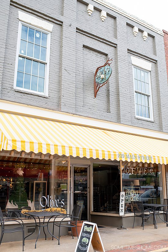 Front of a store painted grey with a white and yellow striped awning on Main Street ain Fort Mill, South Carolina.